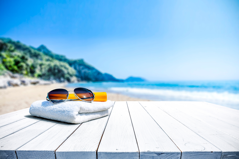 sunblock, towel, and sunglasses by the beach